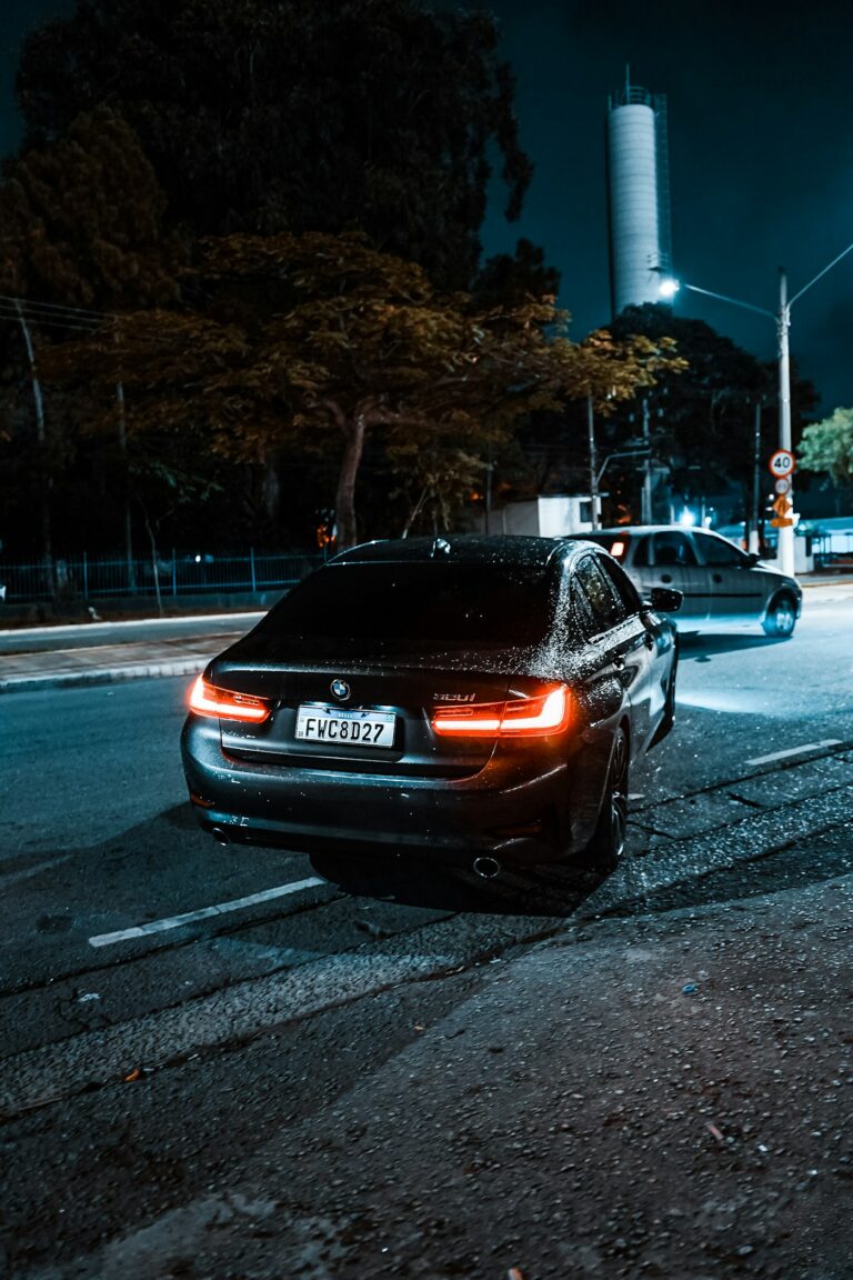 Black luxury sedan with tail lights on at night